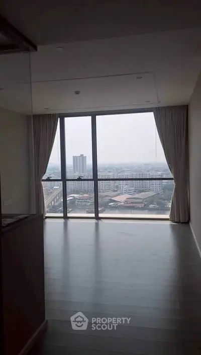 Spacious living room with floor-to-ceiling windows offering a stunning city view.