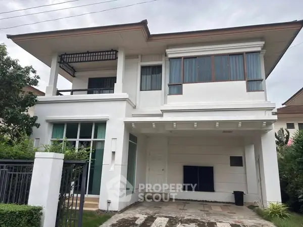Modern two-story white house with large windows and a spacious driveway.