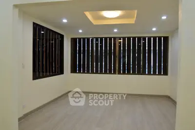 Spacious empty room with modern lighting and large windows, perfect for customization.