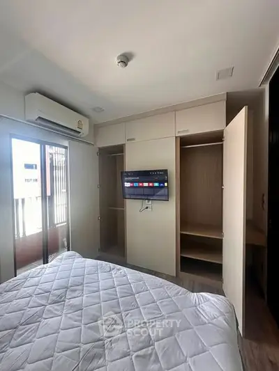 Modern bedroom with built-in wardrobe and wall-mounted TV in a stylish apartment.