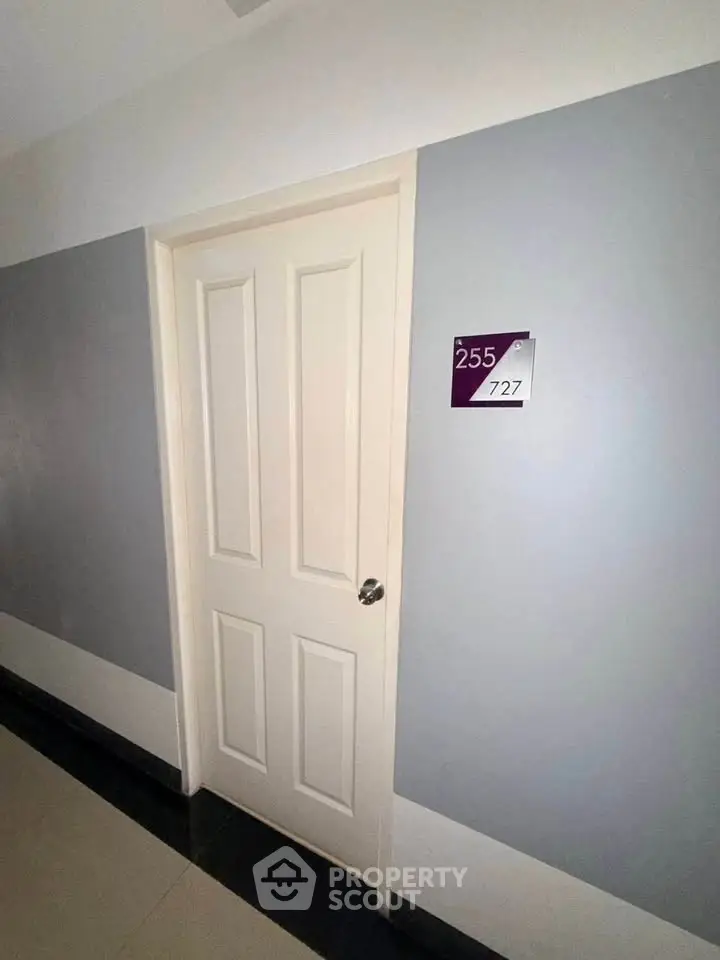 Modern apartment door with room number 727 in a sleek hallway.