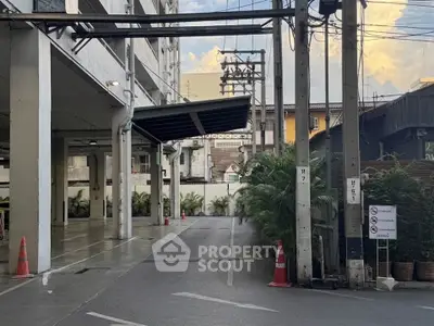 Spacious parking area with modern building exterior and lush greenery.