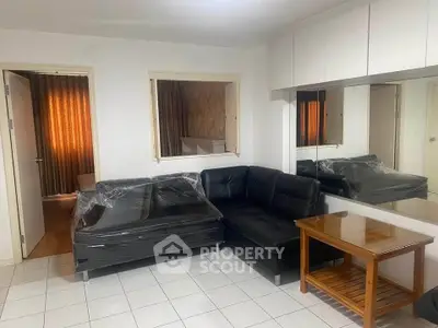 Cozy living room with black leather sofa and mirrored wall