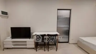 Modern minimalist bedroom with TV and dining area, perfect for cozy living.