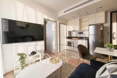 Modern open-layout living room with kitchen, featuring sleek appliances and stylish decor.