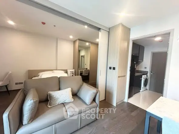Modern studio apartment with sleek design, featuring a cozy living area and compact kitchen with washing machine.