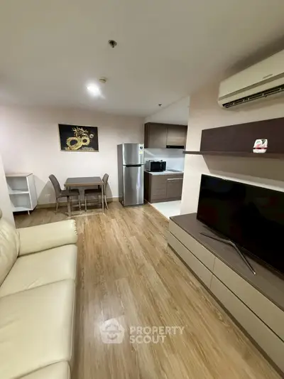 Modern living room with open kitchen, featuring sleek furniture and wooden flooring for a cozy ambiance.