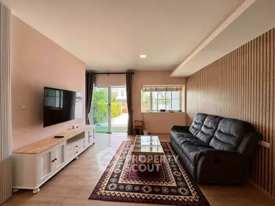 Spacious living room with modern decor and garden view, featuring a sleek TV setup and comfortable seating.