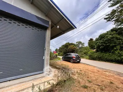 Charming roadside property with secure garage and lush greenery, ideal for business or residential use.