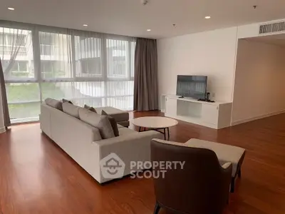 Spacious modern living room with large windows and elegant furniture in a luxury apartment.