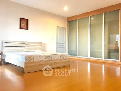 Spacious bedroom with wooden flooring and large sliding closet doors.