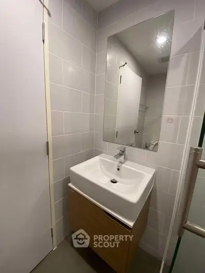 Modern bathroom with sleek sink and large mirror in a compact space.