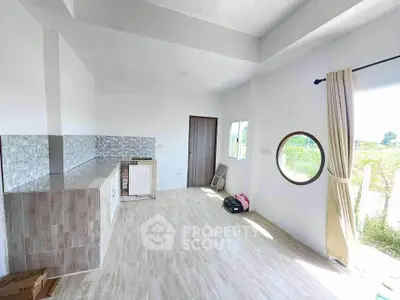 Bright and airy room with modern tiled flooring and unique round window, perfect for customization.