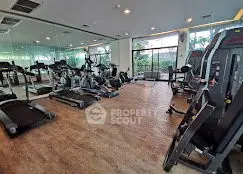 Spacious gym with modern equipment and large windows for natural light.