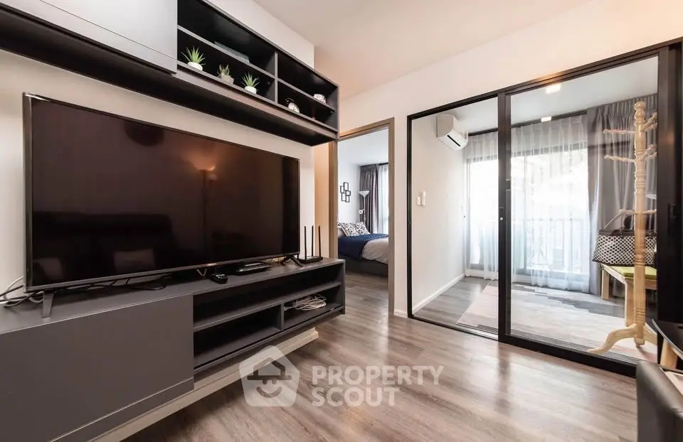 Modern living room with sleek TV unit and view into cozy bedroom