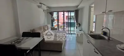 Modern living room with cozy sofa and open kitchen layout, featuring large windows for natural light.