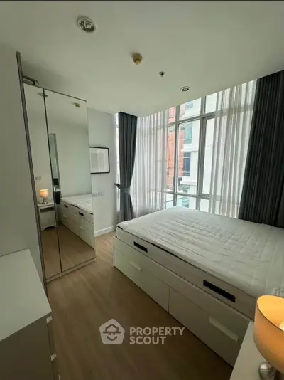 Modern bedroom with large windows and mirrored wardrobe in a stylish apartment.