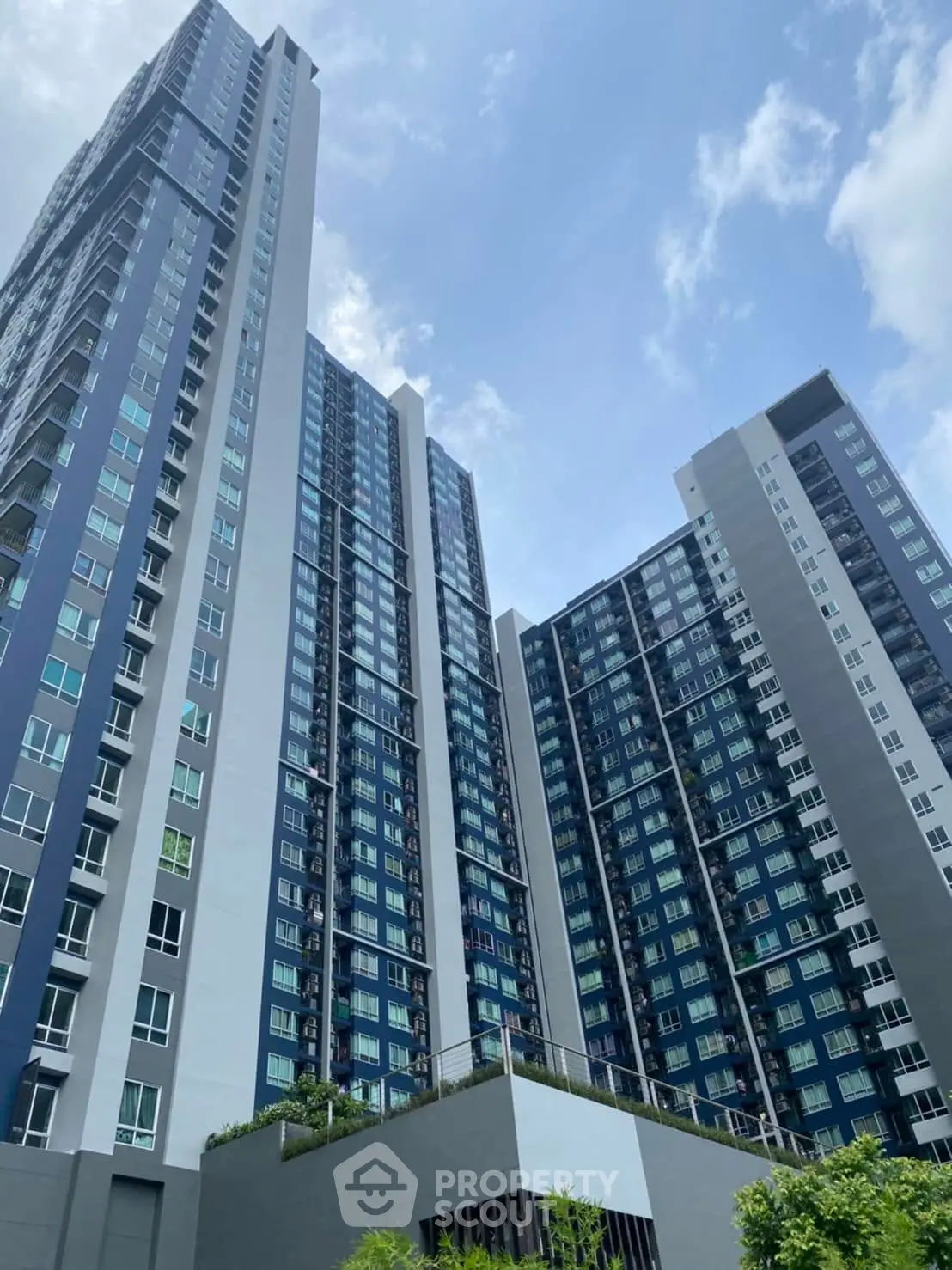 Modern high-rise residential building with sleek architecture and blue sky backdrop.