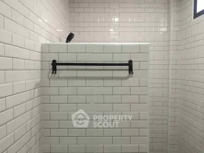 Modern bathroom with white subway tiles and sleek black towel rack.