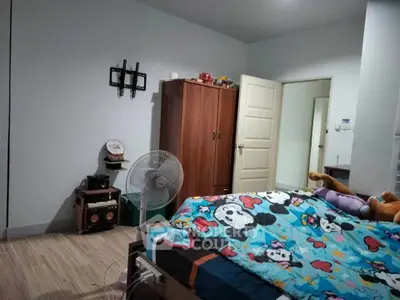 Cozy bedroom with colorful bedding and wooden wardrobe, perfect for a comfortable living space.
