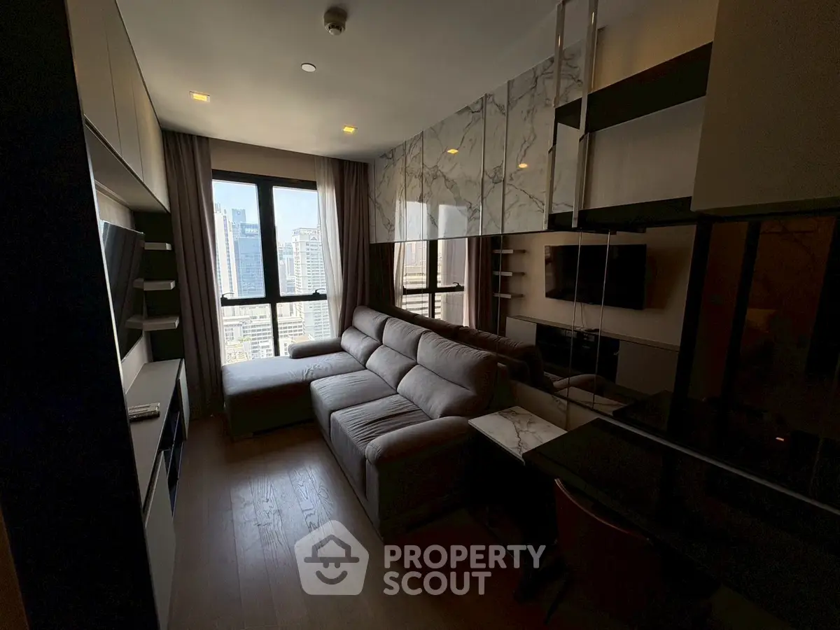 Modern living room with large sofa and city view, featuring stylish decor and ample natural light.