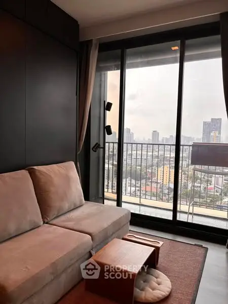 Modern living room with city view and balcony access, featuring sleek furniture and large windows.