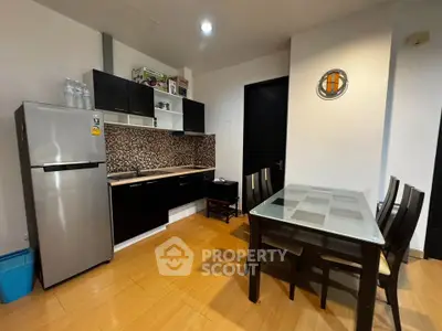 Modern kitchen with sleek black cabinets and dining area in stylish apartment.
