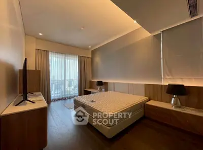 Spacious bedroom with large window and modern furnishings in luxury apartment.