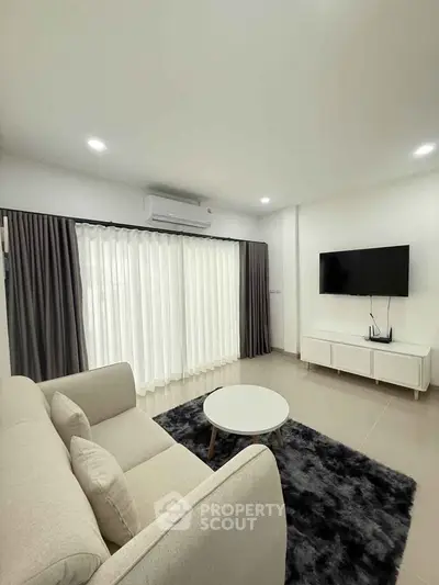 Modern living room with sleek furniture and large window, perfect for relaxation and entertainment.