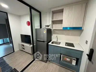 Modern compact kitchen with sleek appliances and stylish cabinetry in a contemporary apartment.