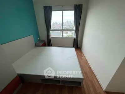 Modern bedroom with city view, featuring a sleek bed and large window for natural light.