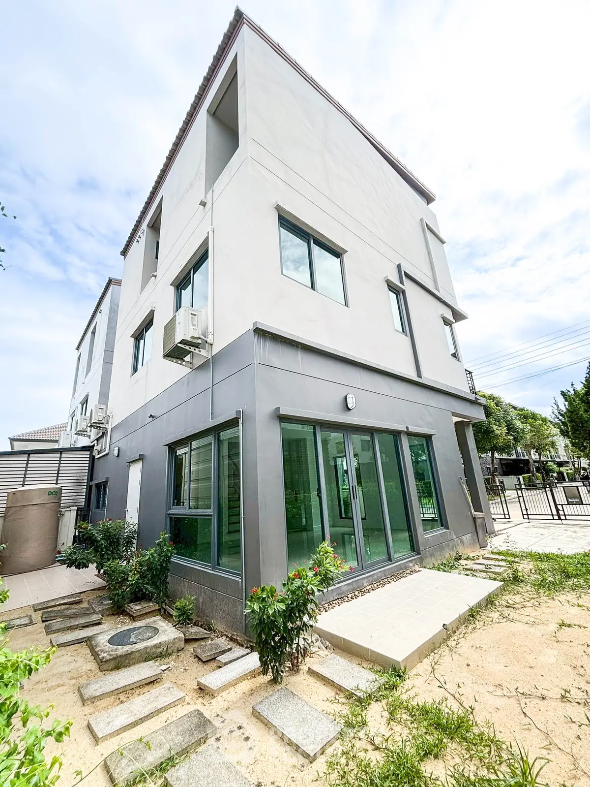 Modern three-story building with large windows and landscaped garden in a serene neighborhood.