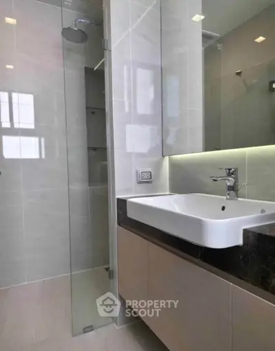 Modern bathroom with sleek design featuring glass shower and stylish sink.