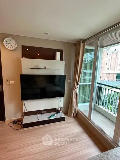 Modern living room with large TV and balcony view in urban apartment