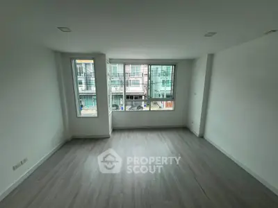 Spacious empty room with large windows and modern flooring, ideal for customization.