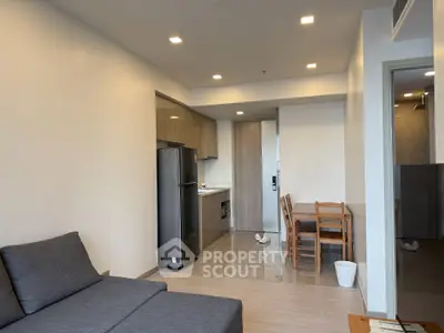 Modern open-plan living room with sleek kitchen and dining area, featuring neutral tones and contemporary furniture.