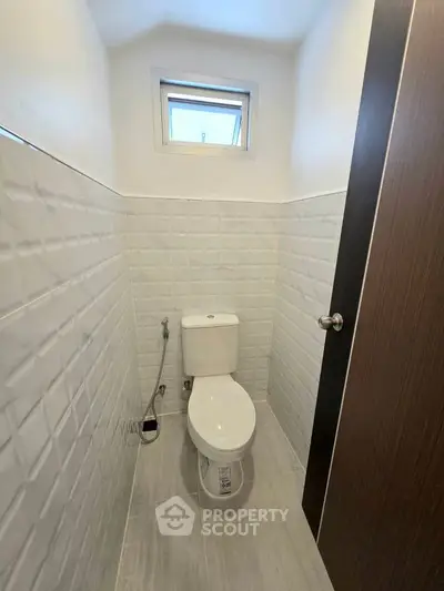 Compact modern bathroom with white tiles and small window