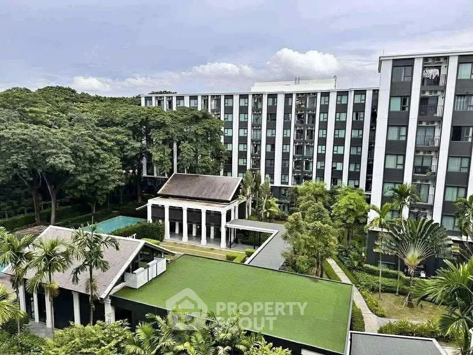 Modern apartment complex with lush greenery and outdoor amenities.