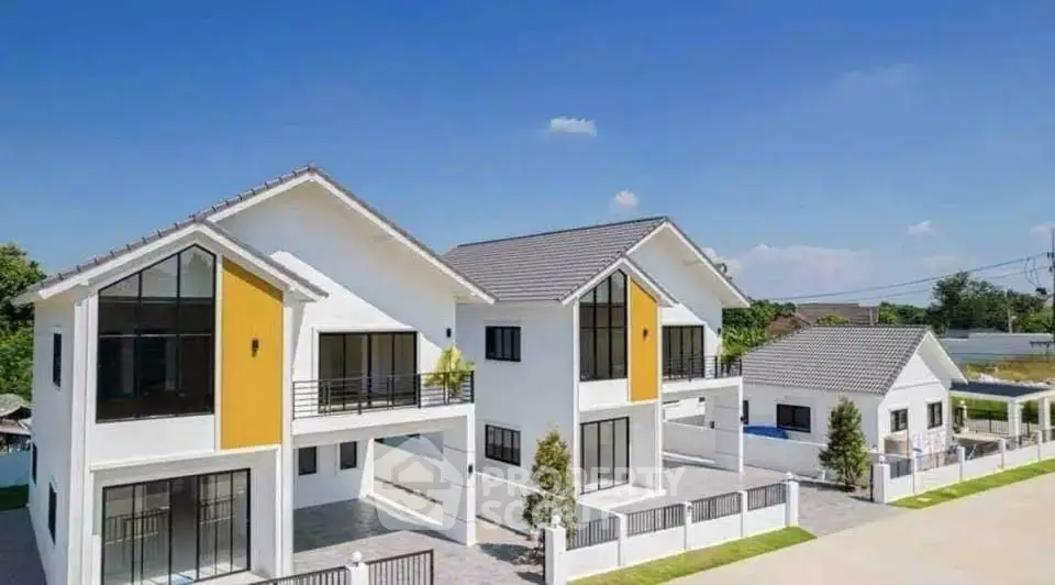 Modern two-story white houses with large windows and spacious driveways in a serene neighborhood.