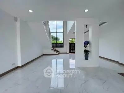 Spacious modern living room with high ceilings and large windows offering natural light and scenic views.