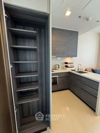 Modern kitchen with sleek cabinets and open shelving in a contemporary apartment.
