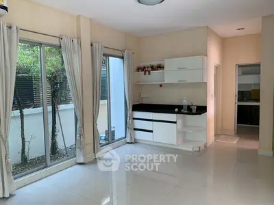 Spacious modern living room with large windows and sleek kitchen area