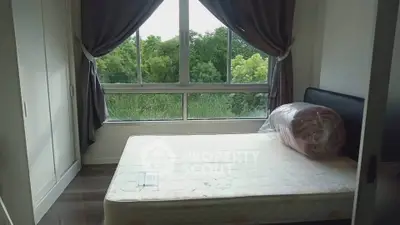 Cozy bedroom with large window and lush green view, perfect for relaxation.