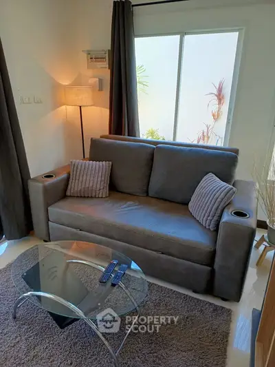 Cozy living room with modern sofa and glass coffee table, perfect for relaxation.