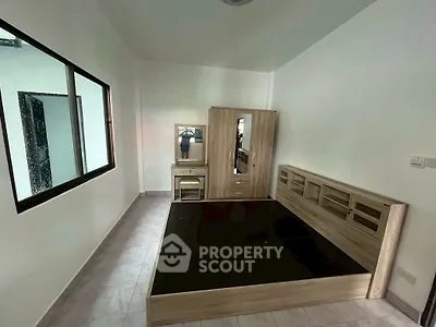 Spacious bedroom with modern wooden furniture and large window for natural light.