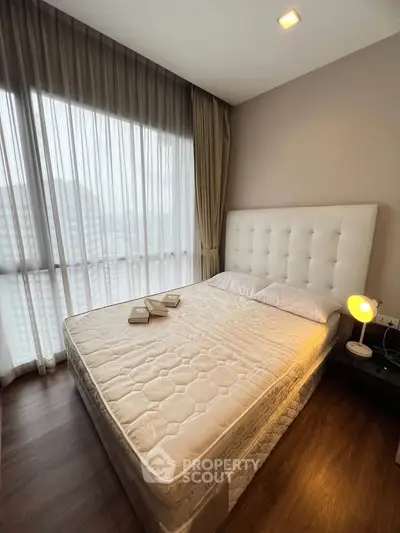 Cozy bedroom with large window and elegant decor, perfect for relaxation.