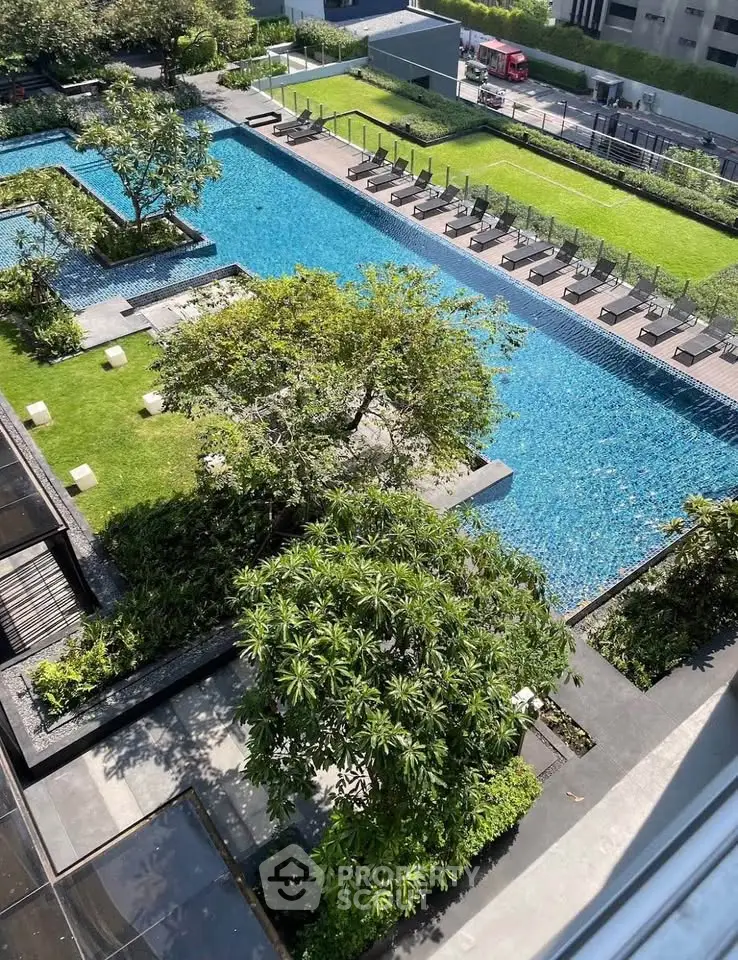 Luxurious outdoor pool area with lush greenery and sun loungers in a modern residential complex.