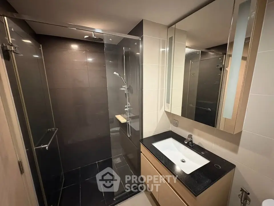 Modern bathroom with sleek glass shower and elegant vanity in contemporary apartment.