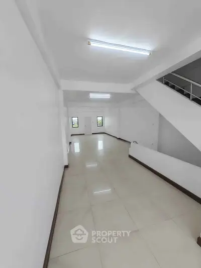 Spacious open-plan interior with tiled flooring and modern staircase, ideal for versatile living or office space.