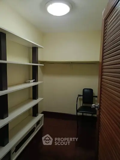 Spacious walk-in closet with ample shelving and seating, perfect for organized storage.
